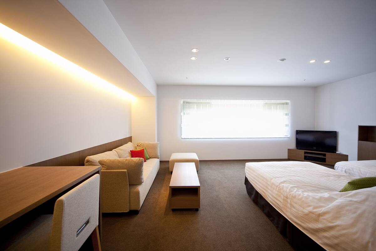 Een moderne hotelkamer met een bank, een bed, een televisie en een bureau.