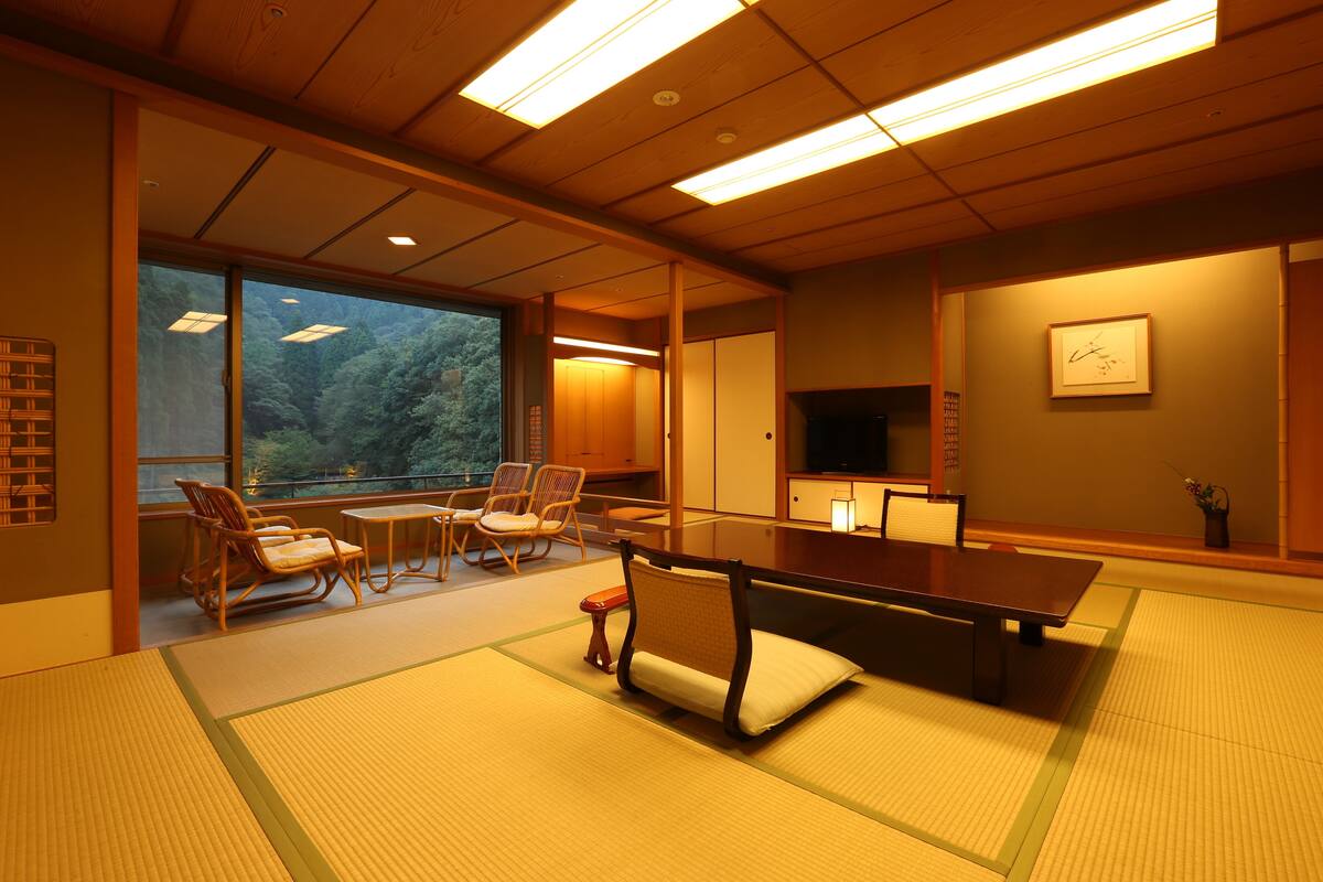 Een traditionele Japanse kamer met tatami vloerbedekking, een lage tafel en houten stoelen.