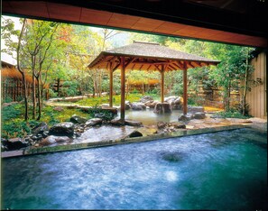 A tranquil indoor garden with a stone water feature, a wooden gazebo, and a clear pool. - Nishimuraya Hotel Shogetsutei (Toyooka)