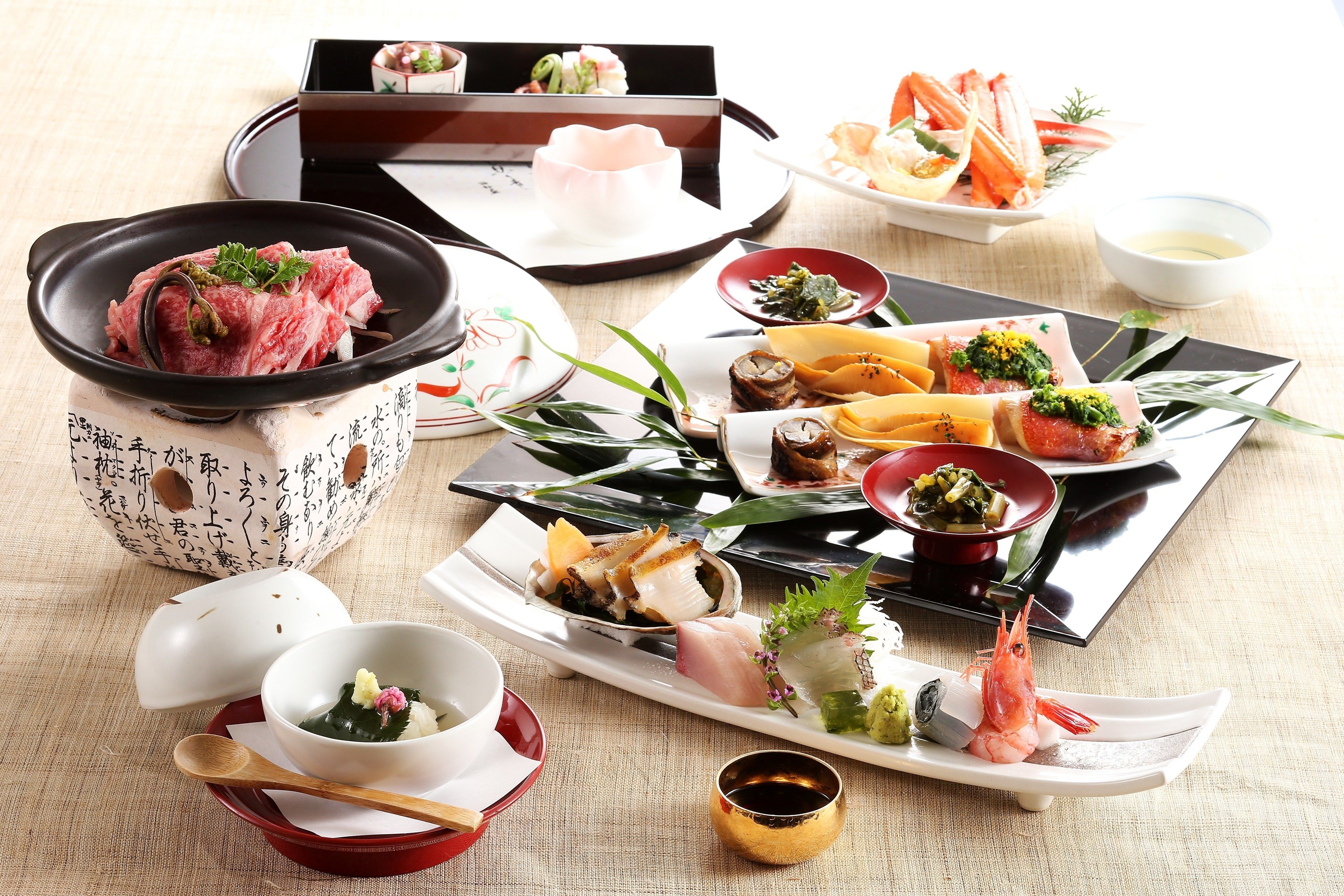 A variety of Japanese dishes arranged on a table, including sushi, sashimi, and other delicacies, with chopsticks and small bowls.