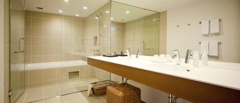 Un baño moderno con cabina de ducha de vidrio, un espejo grande y un mueble de tocador de madera.