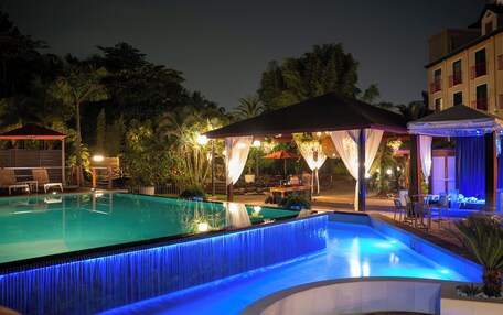 A swimming pool with a waterfall feature, surrounded by outdoor seating and covered areas.