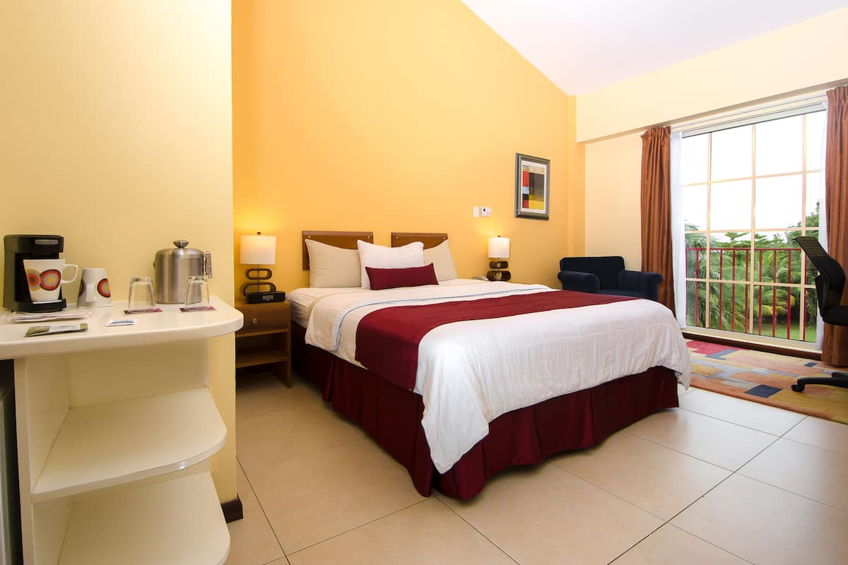 A hotel room with a bed, bedside tables, a desk, a chair, and a window with a view.
