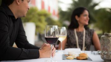 Una mesa de comedor con una copa de vino, pasteles y un jarrón decorativo.