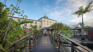 A wooden bridge leading to a hotel with multiple balconies and a pool area. - Royal Torarica Hotel (Paramaribo)