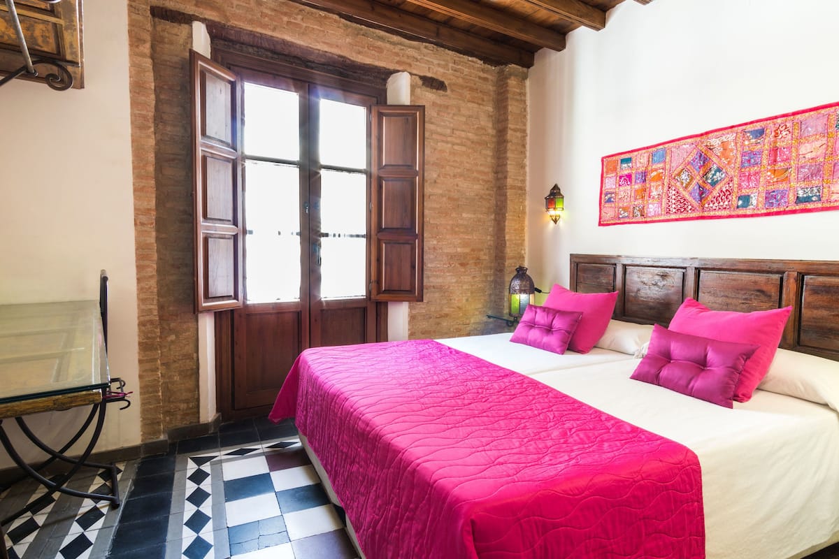 Un dormitorio con una cama grande, un cabecero de madera, un tapiz colorido y un suelo a cuadros.