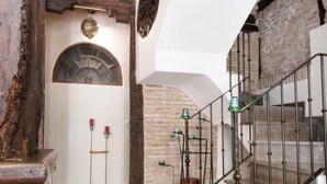 Una escalera con barandilla de metal, pared de piedra y estructura de vigas de madera.