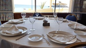 Mesa de comedor lista para una comida con vista al mar.