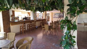 Zona de bar con mobiliario de mimbre y suelo de baldosas.