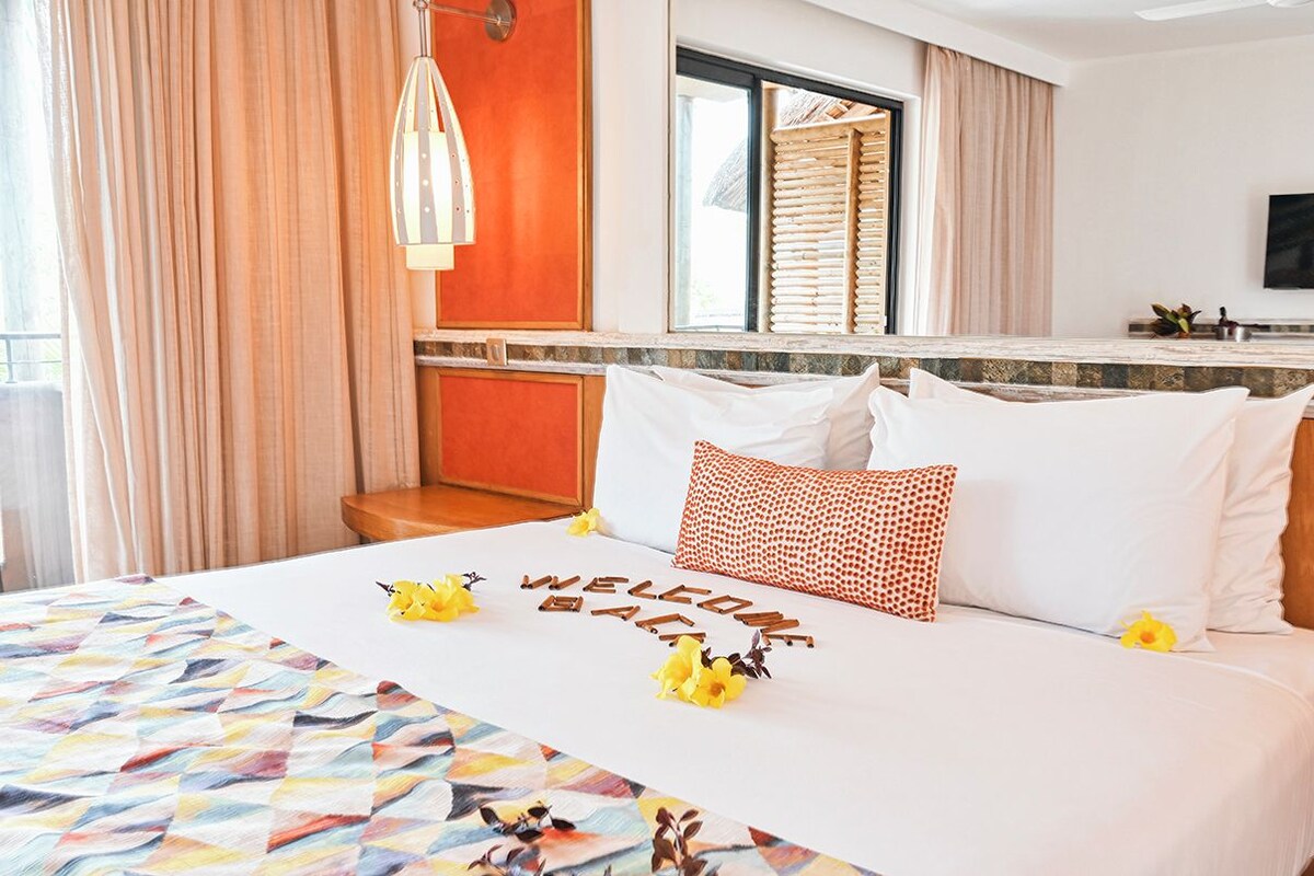 Une chambre d’hôtel avec un lit, une fenêtre avec des rideaux, une télévision et un petit coin cuisine.
