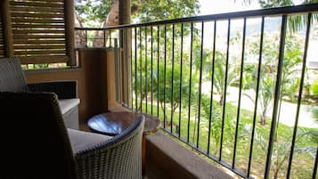 A balcony with wicker furniture and a view of a lush garden.