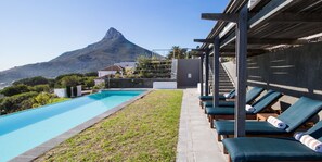 A swimming pool with lounge chairs and a mountain view. - The Crystal Apartments (Cape Town)