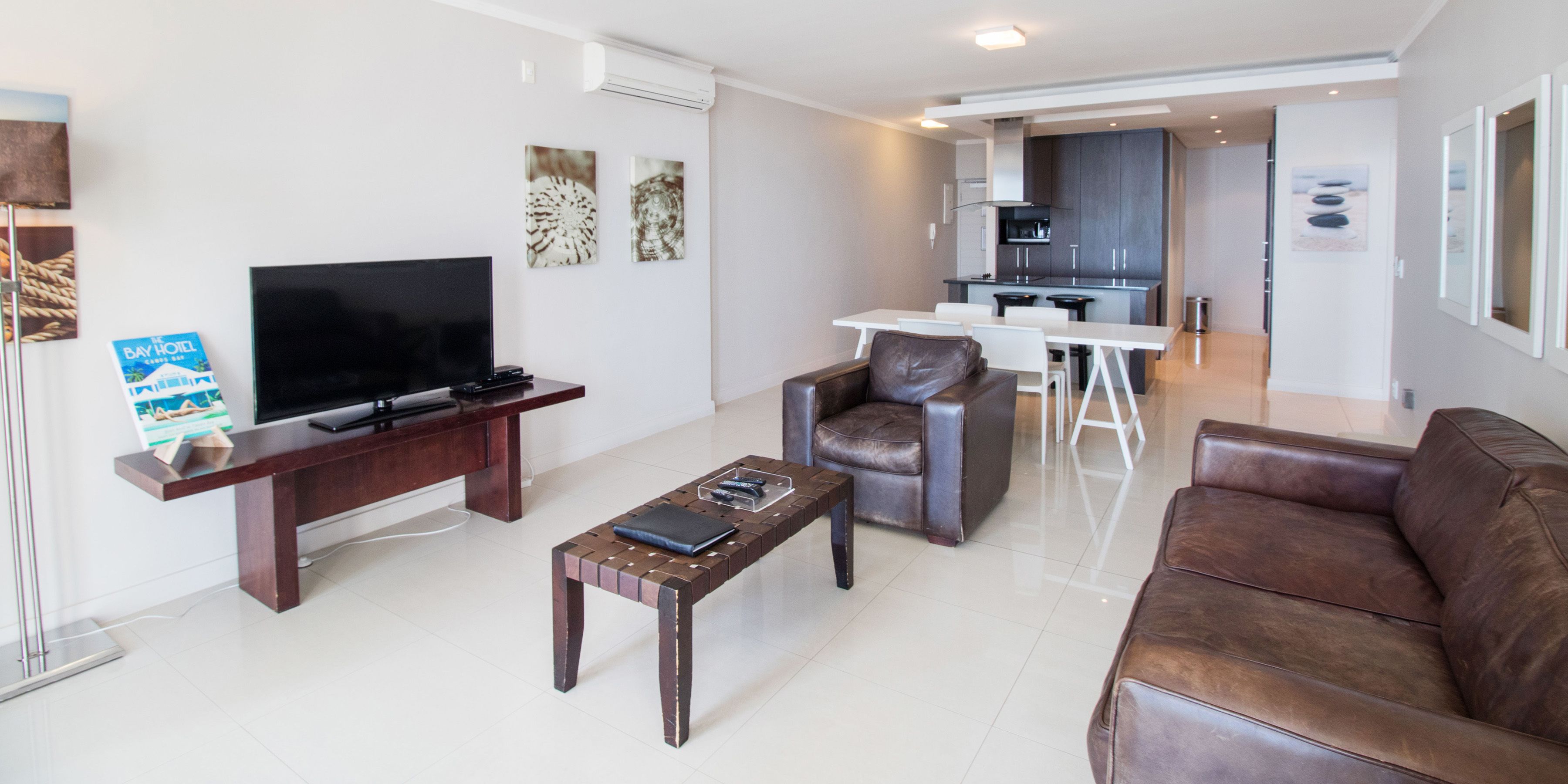 A modern living room with a TV, a coffee table, a sofa, and a dining area with chairs.