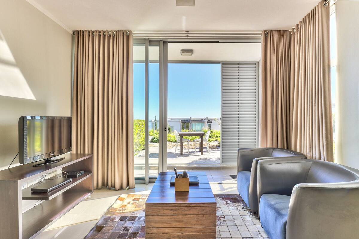 A modern living room with a flat-screen TV, a wooden coffee table, and a sofa.