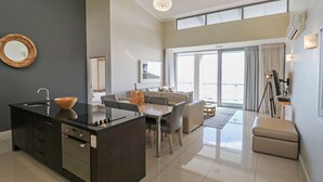 Eine moderne Küche mit Kochinsel, ein Essbereich mit Tisch und Stühlen sowie ein Balkon mit Aussicht.