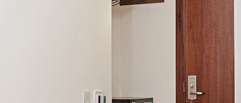 Una habitación con puerta de madera, un estante con microondas y un mueble pequeño.