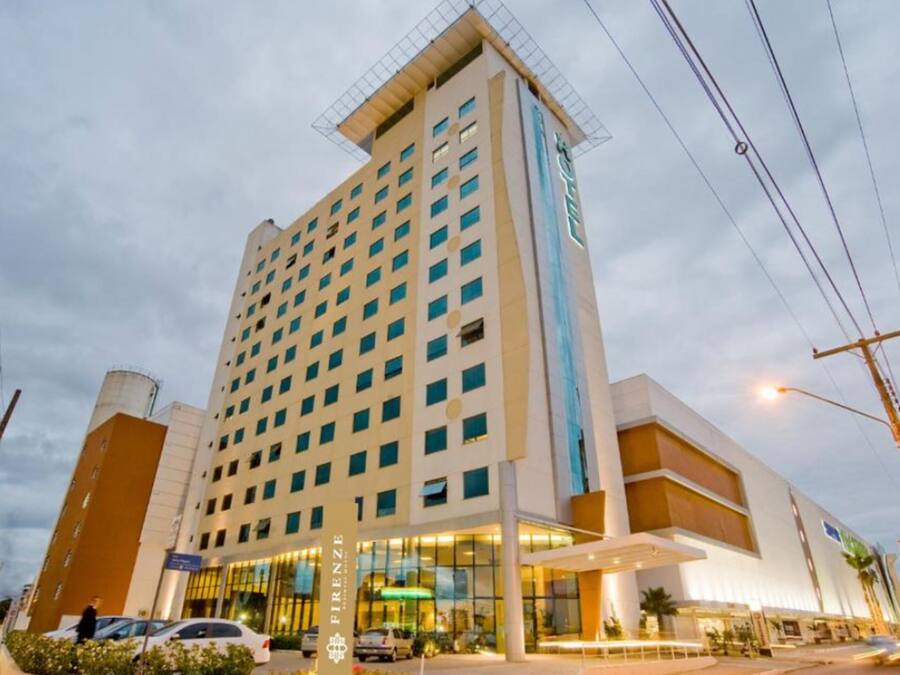 Um hotel com vários andares e design moderno, com entrada destacada e portas de vidro, onde se vê o nome da marca.