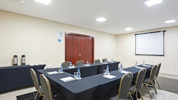 A conference room with a long table, chairs, a projector screen, and a door.