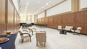 A spacious conference room with rows of chairs, a buffet table, and a long table with chairs. - Firenze Business Hotel (Palhoça)
