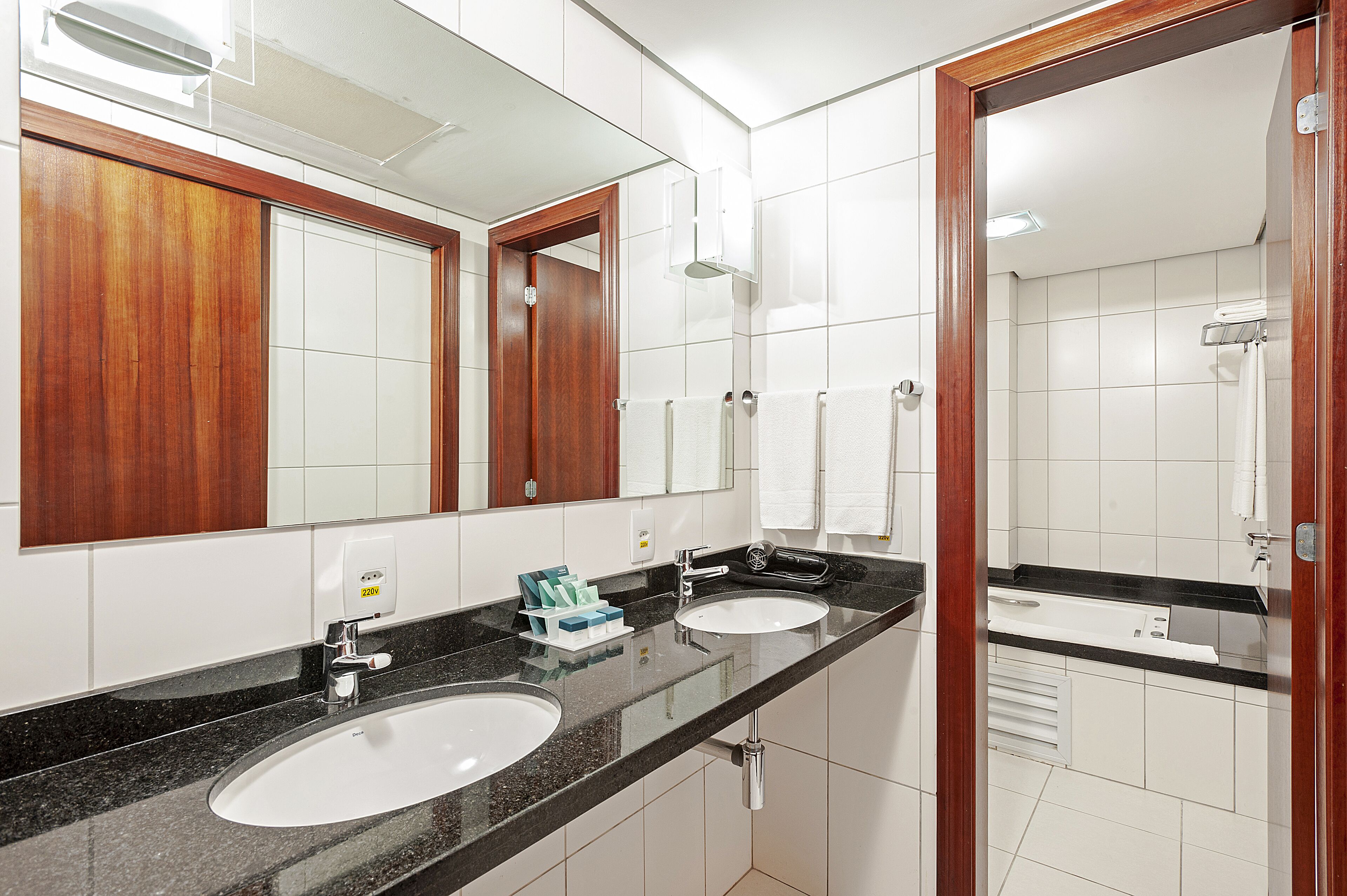 A bathroom with two sinks, a mirror, and a shower.