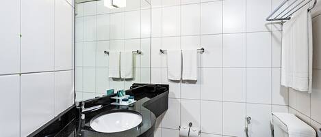 A modern bathroom with a black sink, white toilet, and a mirror above the sink.