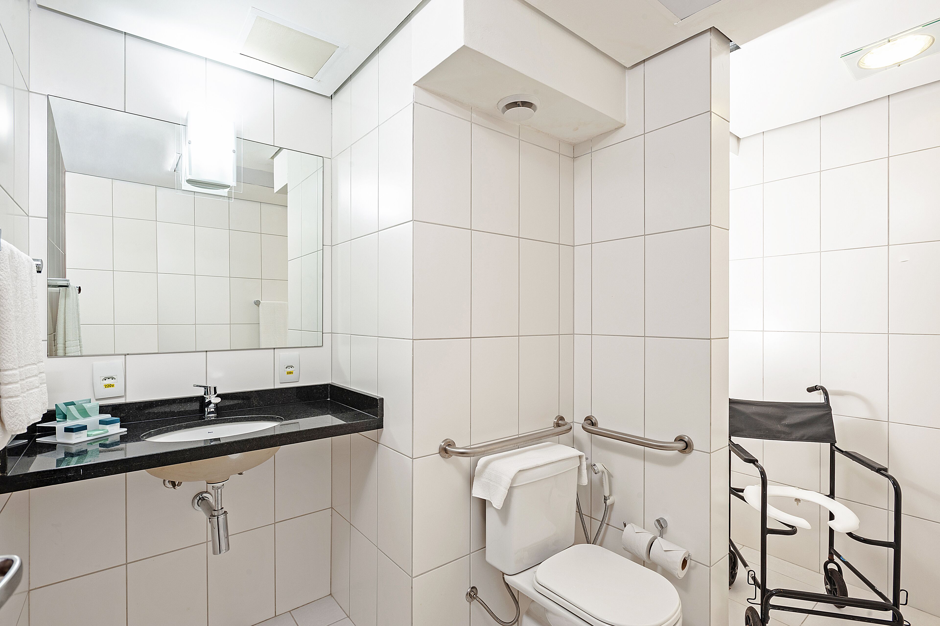 Une salle de bain moderne équipée d’un lavabo, d’un miroir, de toilettes et d’une douche.