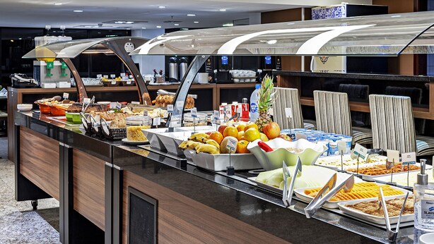 A buffet with various food items and a coffee station. - Firenze Business Hotel (Palhoça)
