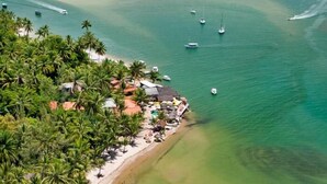 Eine Küstenlandschaft mit Strand, Palmen und Booten im Wasser.