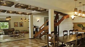 Ein geräumiger Essbereich mit einem großen Holztisch und Stühlen, einem Schachbrettmuster-Boden und einer Treppe zu einer anderen Ebene.