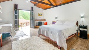 Ein Schlafzimmer mit einem großen Bett, Holzboden, einem Fenster und Blick ins Freie.