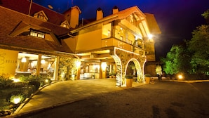 A hotel with a traditional European architectural style, featuring a stone facade, a balcony, and a well-lit entrance. - Villa Bella Hotel & SPA Gramado (Gramado)
