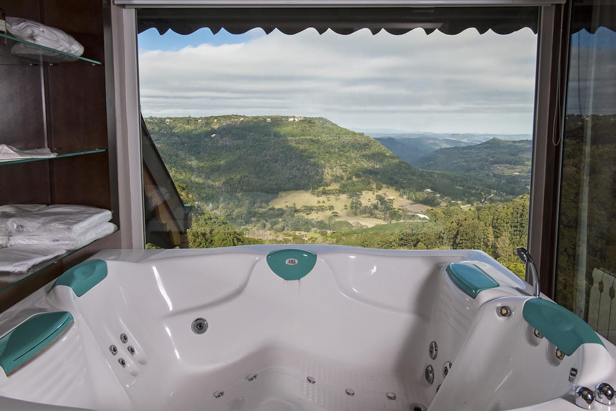 A bathroom with a bathtub and a view of a mountainous landscape through a large window.