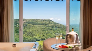 A room with a glass table, two glasses of champagne, a bottle, and a plate of strawberries. - Villa Bella Hotel & SPA Gramado (Gramado)