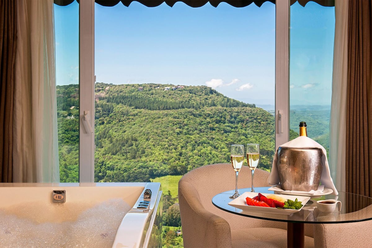 A room with a glass table, two glasses of champagne, a bottle, and a plate of strawberries.