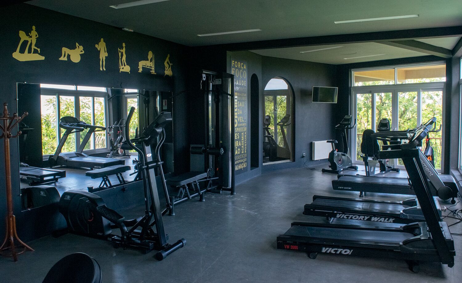 Ein Fitnessstudio mit Laufbändern, Kraftgeräten und einem großen Fenster, das für natürliches Licht sorgt.