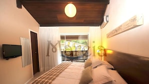 A bedroom with a bed, a television on the wall, a window with curtains, and a ceiling light. - Pousada Mareia (Cairu)