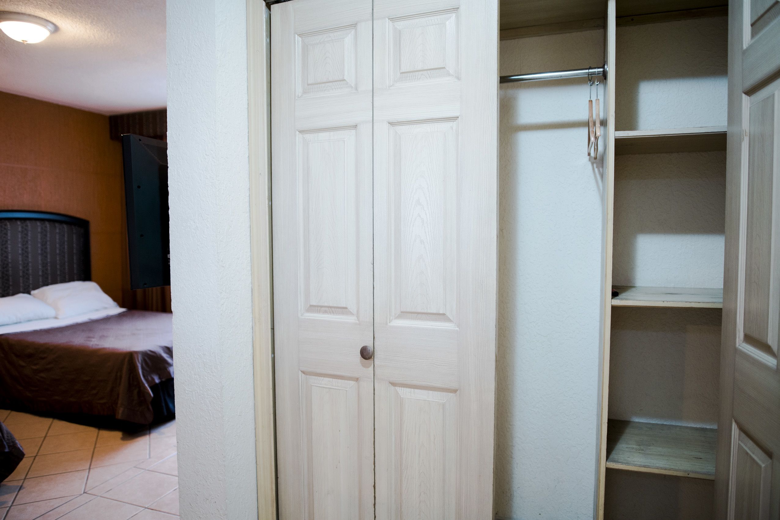 Una habitación de hotel con cama, armario y estantería.