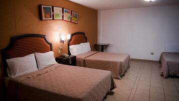 Habitación de hotel con dos camas, una mesita pequeña y un reloj en la pared.