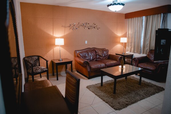 A living room with a brown leather sofa, two armchairs, a coffee table, and two floor lamps.