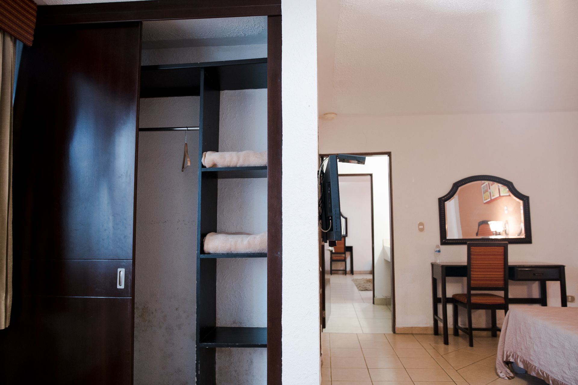 A hotel room with a wardrobe, a desk with a chair, and a bed.