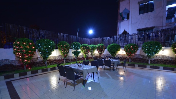 An outdoor dining area with tables and chairs, surrounded by trees with lights, under a night sky. - The Legend Inn Nagpur (Nagpur)