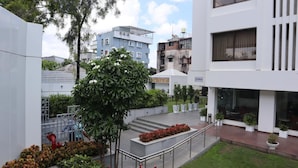 A modern building with a flat roof, a staircase leading to a second floor, and a small garden area with potted plants and a tree. - The Legend Inn Nagpur (Nagpur)