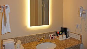 A hotel bathroom with a sink, mirror, towel rack, and a hairdryer.