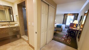 Una habitación de hotel con baño, cama, escritorio y una silla.