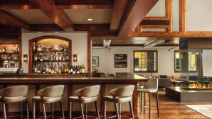 A bar area with a wooden ceiling, bar stools, a well-stocked liquor shelf, and a fire feature. - The Ritz-Carlton Club, Vail (Vail)