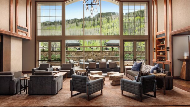A spacious living area with large windows, comfortable seating, and a view of a forested landscape. - The Ritz-Carlton Club, Vail (Vail)