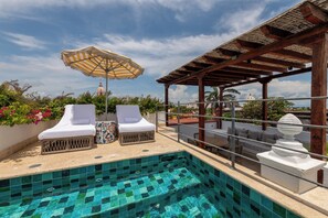 A rooftop pool area with lounge chairs, an umbrella, and a view of a dome in the background. - Casa Pestagua Relais Châteaux (Cartagena)