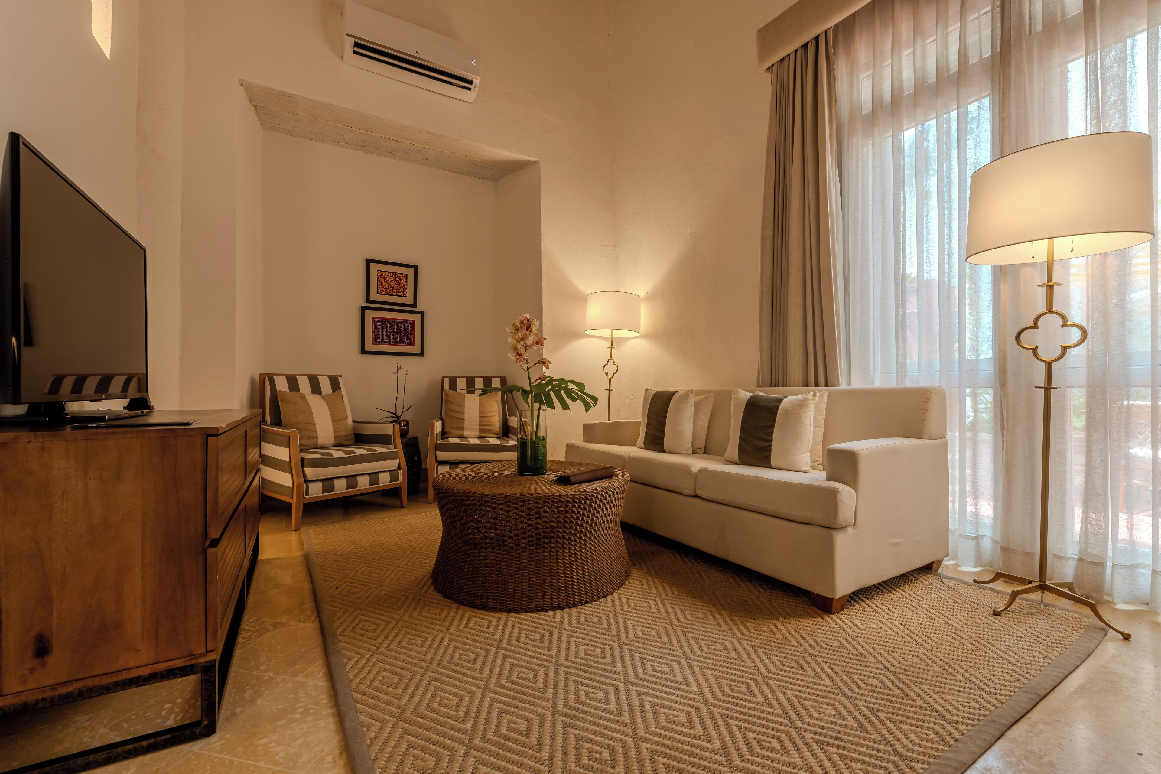A living room with a television, sofa, armchair, and a decorative lamp.