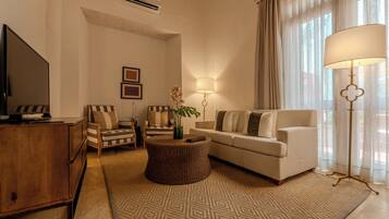 A living room with a television, sofa, armchair, and a decorative lamp.