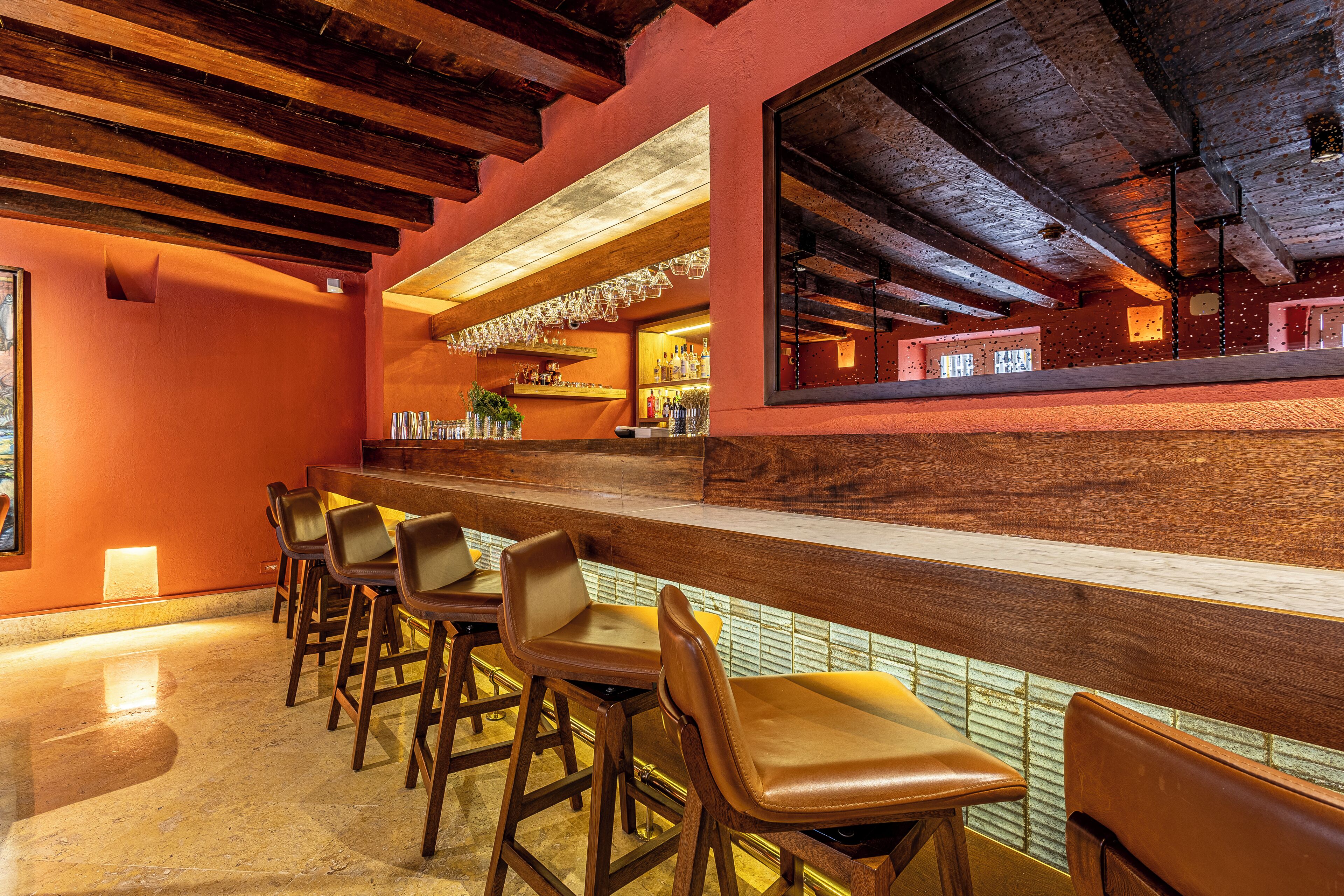 Una zona de bar con taburetes de madera y una barra.